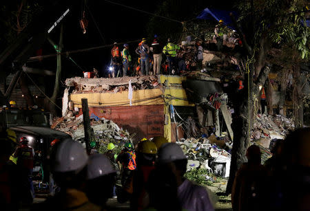 Rescue workers stand on the rubble of a collapsed multi family residential after an earthquake in Mexico City, Mexico September 21, 2017. REUTERS/Daniel Becerril