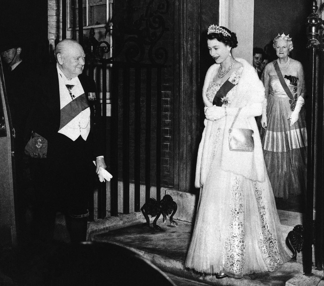 British Prime Minister Winston Churchill bids farewell to Queen Elizabeth II at the end of a dinner he hosted at No. 10 Downing Street in London on April 4, 1955. Lady Churchill stands in the doorway as she follows the queen. (AP)