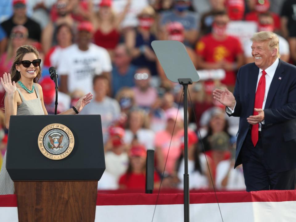 Then-US President Donald Trump laughs as his senior adviser, Hope Hicks, speaks to the crowd during a campaign event at the Ocala International Airport on October 16, 2020 in Ocala, Florida.