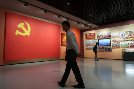 A man walks past a section featuring a flag of Chinese Communist Party next to its loyalty oath at an exhibition marking the 40th anniversary of China's reform and opening up at the Museum of Contemporary Art and Planning Exhibition Centre in Shenzhen, Guangdong province, China December 4, 2018. REUTERS/Thomas Suen