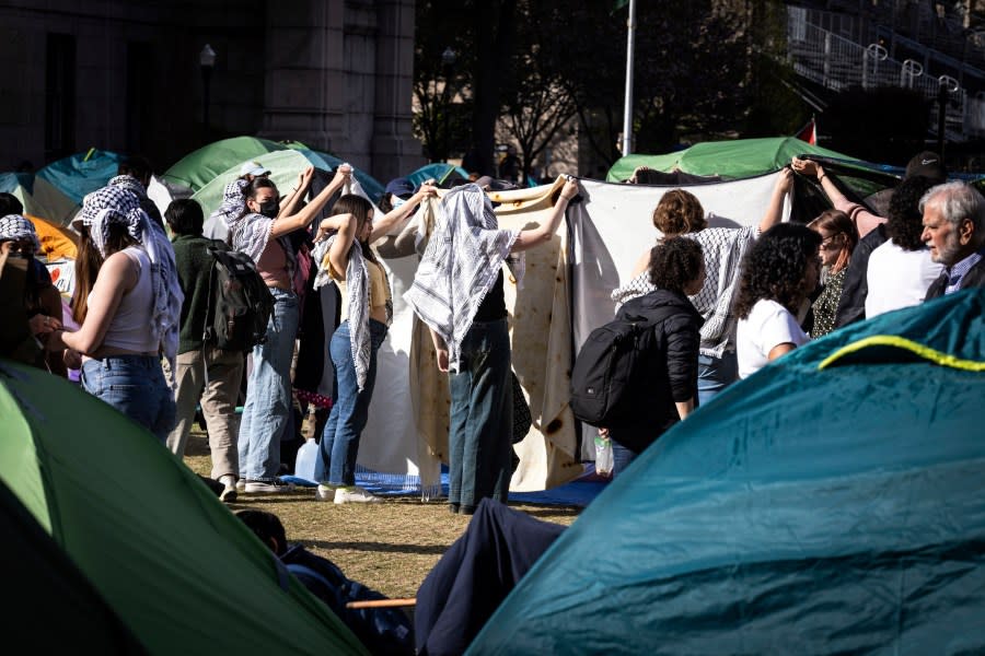 Student protesters hold up sheets as others pray at the pro-Palestinian demonstration encampment at Columbia University in New York on Wednesday April 24, 2024. (AP Photo/Stefan Jeremiah)