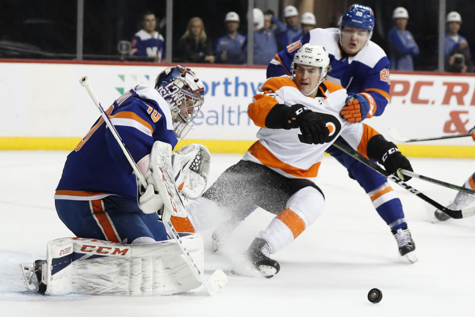 FILE - In This Feb. 11, 2020, file photo, New York Islanders goaltender Semyon Varlamov (40) deflects the puck as Islanders left wing Kieffer Bellows (20) keeps Philadelphia Flyers right wing Nicolas Aube-Kubel (62) away during the first period of an NHL hockey game in New York. The NHL ditched divisional playoffs to go back to the old-school format for its summer postseason and still ended up with all division rivals facing off in the second round. It’s the Flyers against Islanders in the Metropolitan series. (AP Photo/Kathy Willens, File)