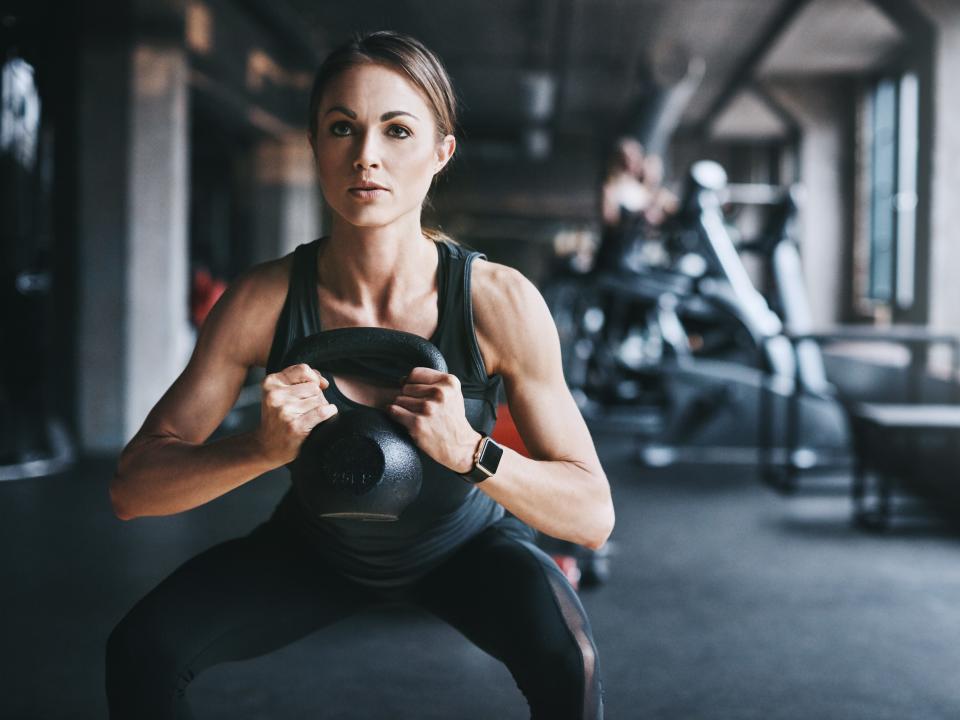 A woman squatting with a kettlebell.