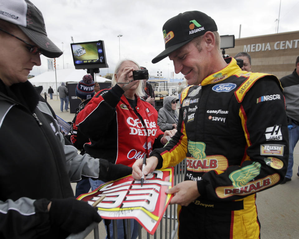NASCAR Cup Series driver Clint Bowyer, right, gives autographs after practicing for the weekend's auto race at Kansas Speedway in Kansas City, Kan., Friday, Oct. 19, 2018. (AP Photo/Orlin Wagner)