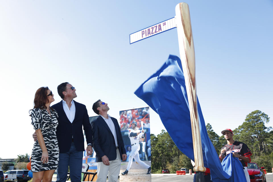 Former New York Mets catcher Mike Piazza, center left, his wife Alicia, left, and Mets COO Jeff Wilpon watch as newly named Piazza Dr., is unveiled during a ceremony in front of the Mets spring training facility, Thursday, Jan. 16, 2020, in Port St. Lucie, Fla. (AP Photo/Wilfredo Lee)