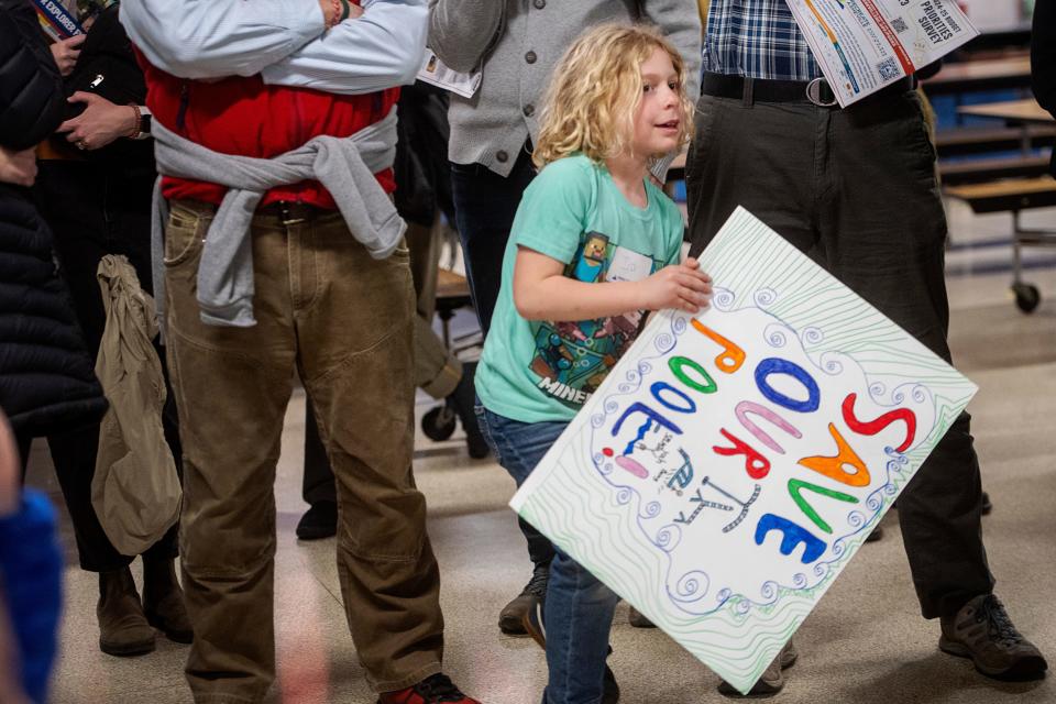 Ira Mandle, 8, moves through the crowd with his sign calling to save the Malvern Hills Pool as community members grill officials on the pool closure, February 21, 2024. “He loves swimming,” said Mandle’s mother, Mary LaBianca, “I don’t know what we’ll do without it.”
