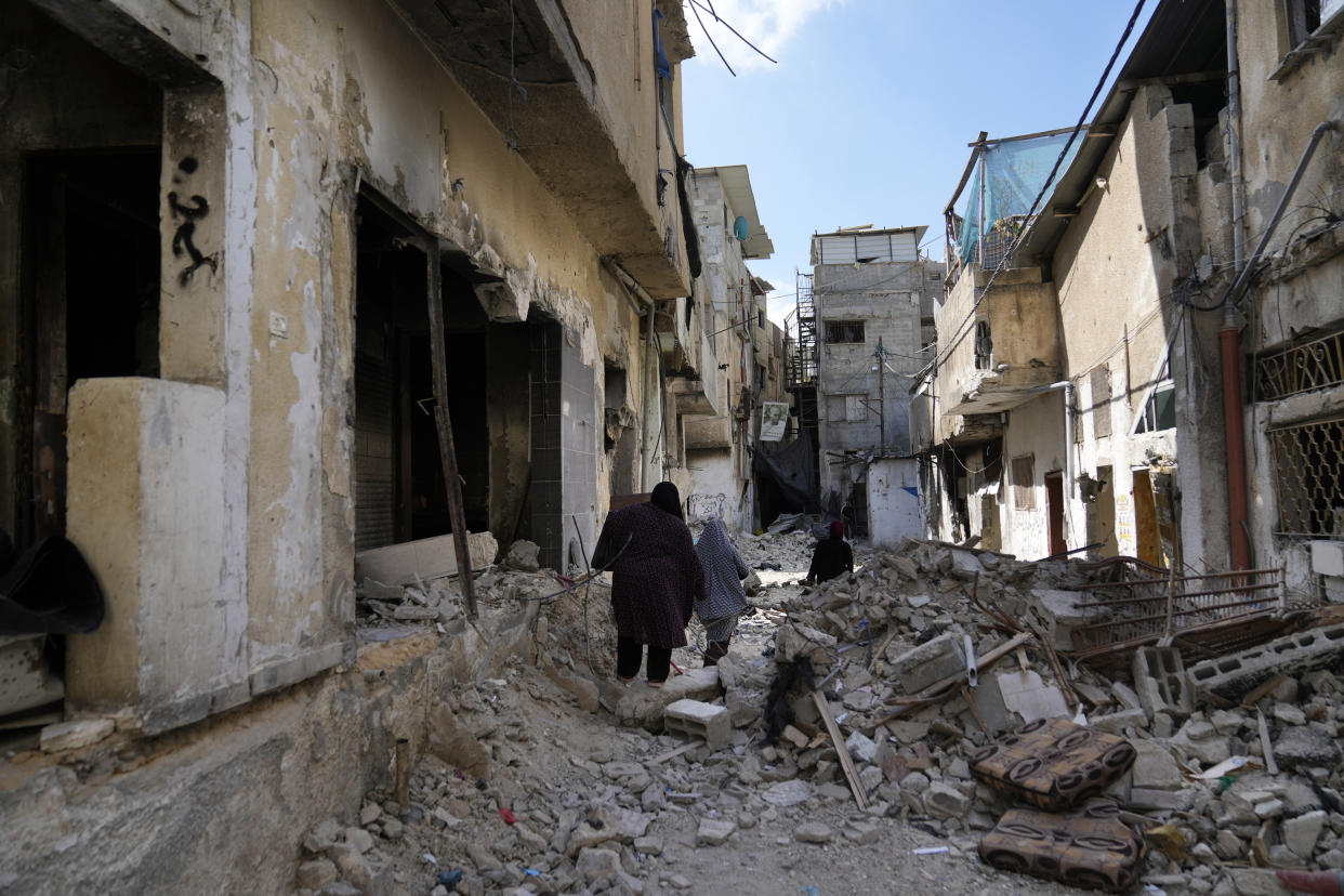 Palestinian refugees walk through the rubble of destroyed houses while they flee their homes during the Israeli army operation in the West Bank refugee camp of Tulkarem, in Tulkarem, Thursday, Sept. 5, 2024. (AP Photo/Nasser Nasser)