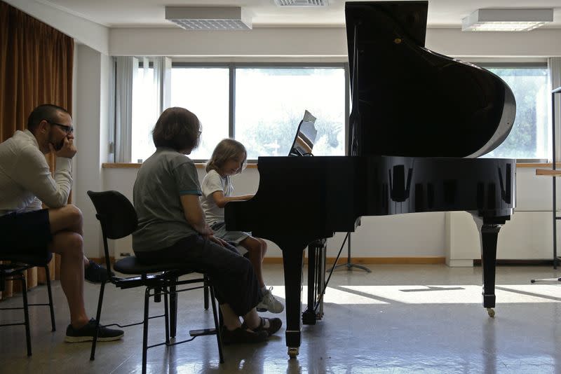 Stelios Kerasidis, 7-year-old pianist and composer, plays the piano during a lesson as his father Fotis Kerasidis watches, at the Athens Megaron Concert Hall in Athens