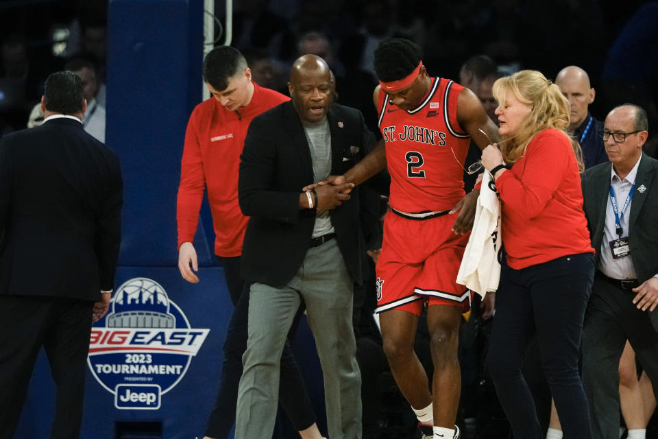 St. John's head coach Mike Anderson, left, and a trainer help AJ Storr (2) after he was hurt during the first half of an NCAA college basketball game against Marquette in the quarterfinals of the Big East Conference Tournament, Thursday, March 9, 2023, in New York. (AP Photo/Frank Franklin II)