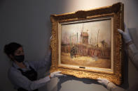 Sotheby's personnel display « Scene de rue à Montmartre » (Street scene in Montmartre), a painting by Dutch master Vincent van Gogh at Sotheby's auction house in Paris, Thursday, Feb. 25, 202. The artwork painted in 1887 is to be on public display for the first time ahead of an auction next month. It has remained in the same family collection for over 100 years, according to the auction house which did not reveal the identity of the owner. (AP Photo/Christophe Ena)