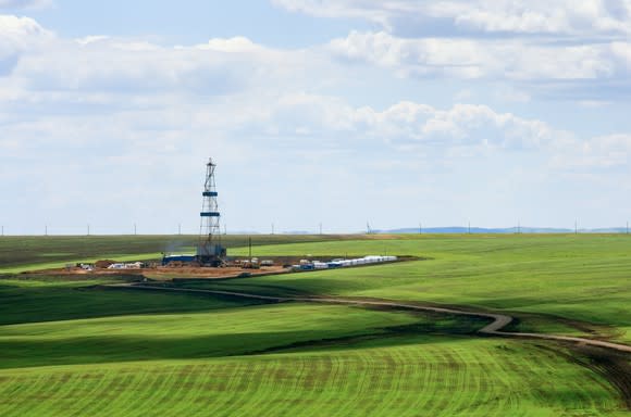 A drilling rig in the middle of a green field.