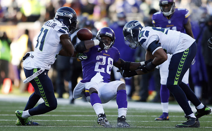Minnesota Vikings running back Adrian Peterson fumbles the ball between Seattle Seahawks strong safety Kam Chancellor and outside linebacker K.J. Wright in the fourth quarter in a NFC Wild Card playoff football game.