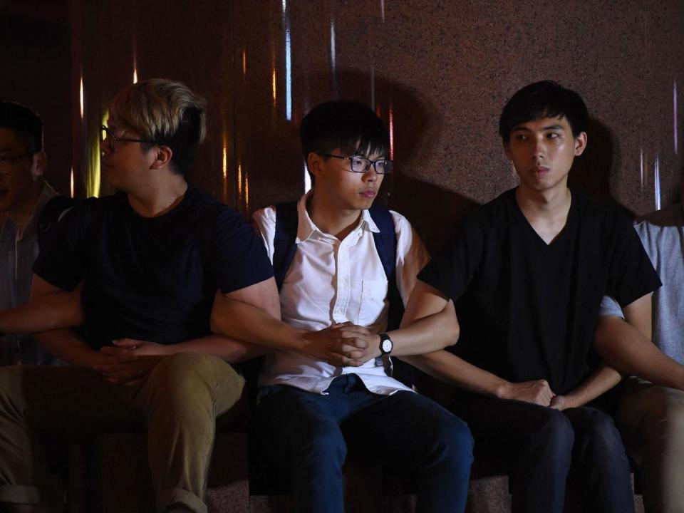 Pro-democracy campaigner Joshua Wong and other demonstrators link arms as police prepare to remove them from the base of the Golden Bauhinia statue (ANTHONY WALLACE/AFP/Getty Images)