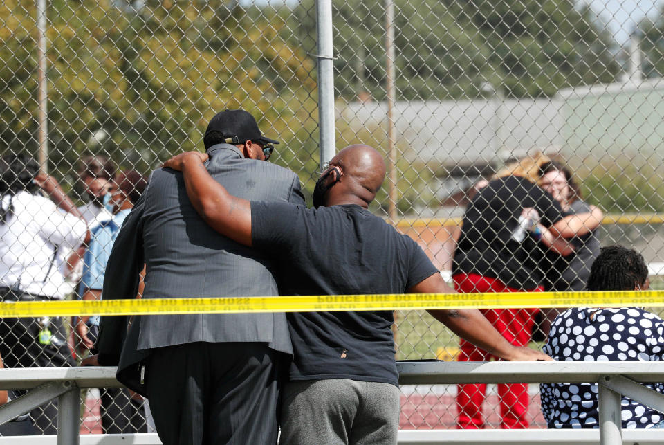 People console one another outside Heritage High School, near the tennis courts, following a shooting at the school, Monday, Sept. 20, 2021, in Newport News, Va. Students were evacuated to the tennis courts and parents were allowed to reunite with them there. (Jonathon Gruenke/The Virginian-Pilot via AP)