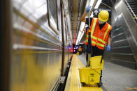 Contractors clean subway cars at the 96th Street station to control the spread of COVID-19, Thursday, July 2, 2020, in New York. Mass transit systems around the world have taken unprecedented — and expensive — steps to curb the spread of the coronavirus, including shutting down New York subways overnight and testing powerful ultraviolet lamps to disinfect seats, poles and floors. (AP Photo/John Minchillo)