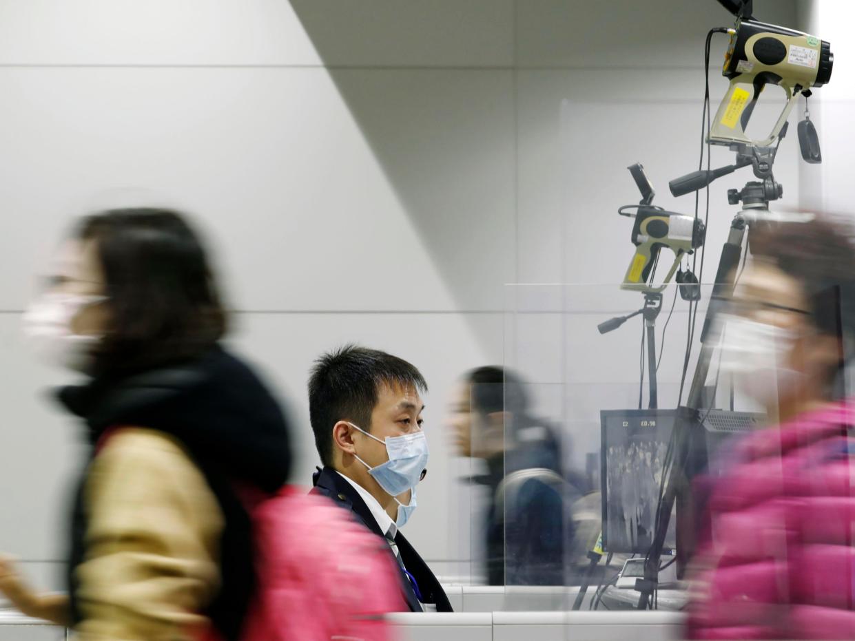 Passengers wearing masks walk by as a quarantine officer, center, monitors a thermography during a quarantine inspection at Kansai international airport in Osaka, western Japan, Wednesday, Jan. 22, 2020. Chinese health authorities urged people in the city of Wuhan to avoid crowds and public gatherings after warning on Wednesday that a new viral illness infecting hundreds of people in the country. Japan, South Korea, the United States and Taiwan have all reported one case each. All of the illnesses were of people from Wuhan or who recently had traveled there. (Kota Endo/Kyodo News via AP)
