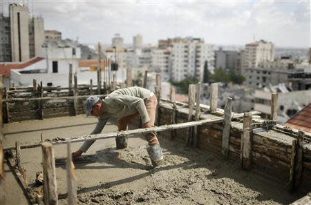 A Palestinian worker flattens cement on the roof of a building under construction in Gaza City September 22, 2013. REUTERS/Mohammed Salem
