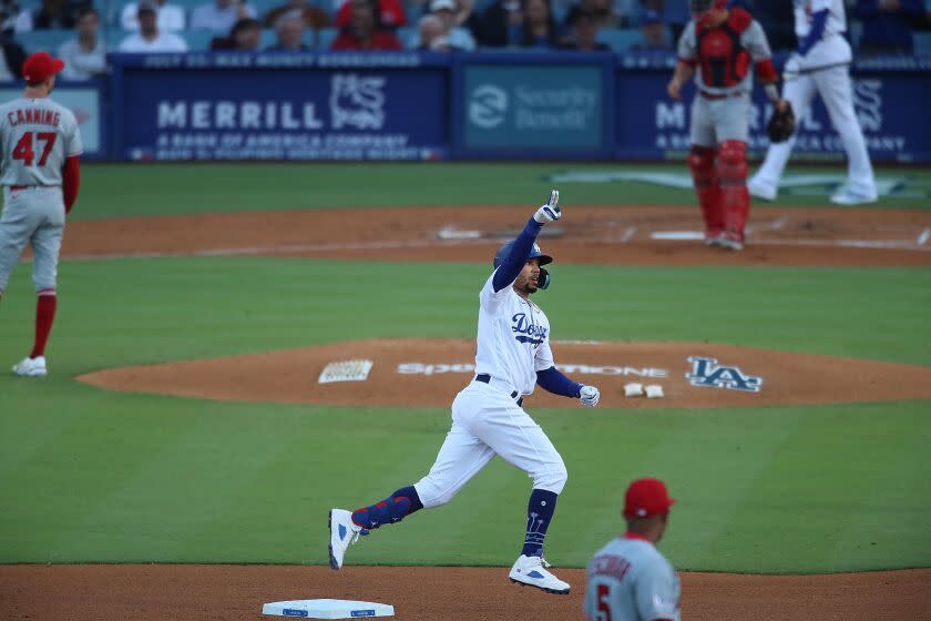 Dodger Mookie Betts points and celebrates his home run as Angels pitcher Griffin Canning and catcher Matt Thaiss look away