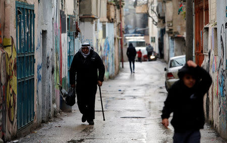 Palestinians walk at Aida refugee camp in the West Bank city of Bethlehem, January 17, 2018. REUTERS/Mussa Qawasma