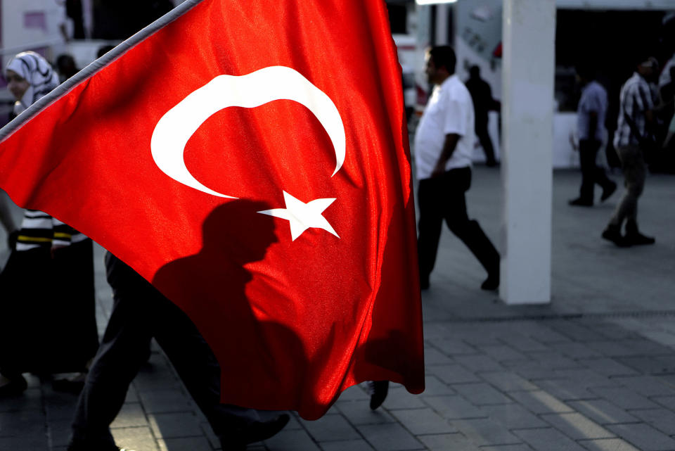 A man’s shadow is seen behind a Turkish flag