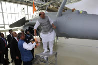 Indian Defense Minister Rajnath Singh has a ritual gesture onto a Rafale jet fighter during an handover cermony at the Dassault Aviation plant in Merignac, near Bordeaux, southwestern France, Tuesday, Oct. 8, 2019. France has delivered to India its first Rafale fighter jet from a series of 36 aircraft purchased in a multi-billion dollar deal in 2016. (AP Photo/Bob Edme)