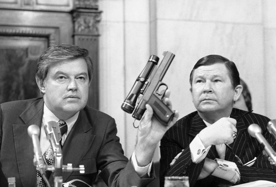 <div class="inline-image__caption"><p>Chairman Frank Church, D-ID, holds up a poison dart gun as co-chairman John G. Tower, R-TX looks at the weapon.</p></div> <div class="inline-image__credit">Henry Griffin/AP</div>