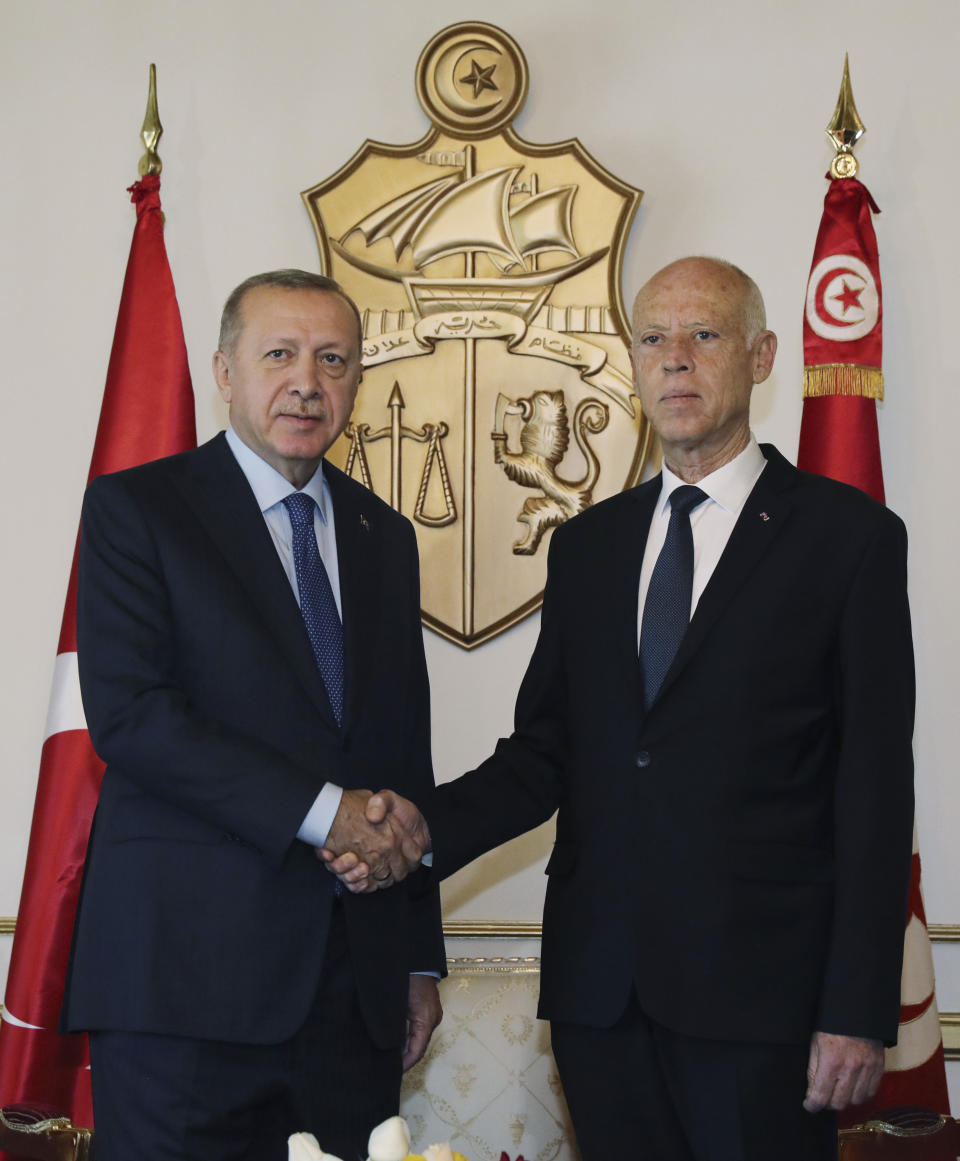 Turkey's President Recep Tayyip Erdogan, left, and Tunisian President Kais Saied shake hands before a meeting, in Tunis, Tunisia, Wednesday, Dec. 25, 2019. Erdogan with top Turkish officials is on an unannounced visit to Tunisia to meet Saied.(Turkish Presidency via AP, Pool)