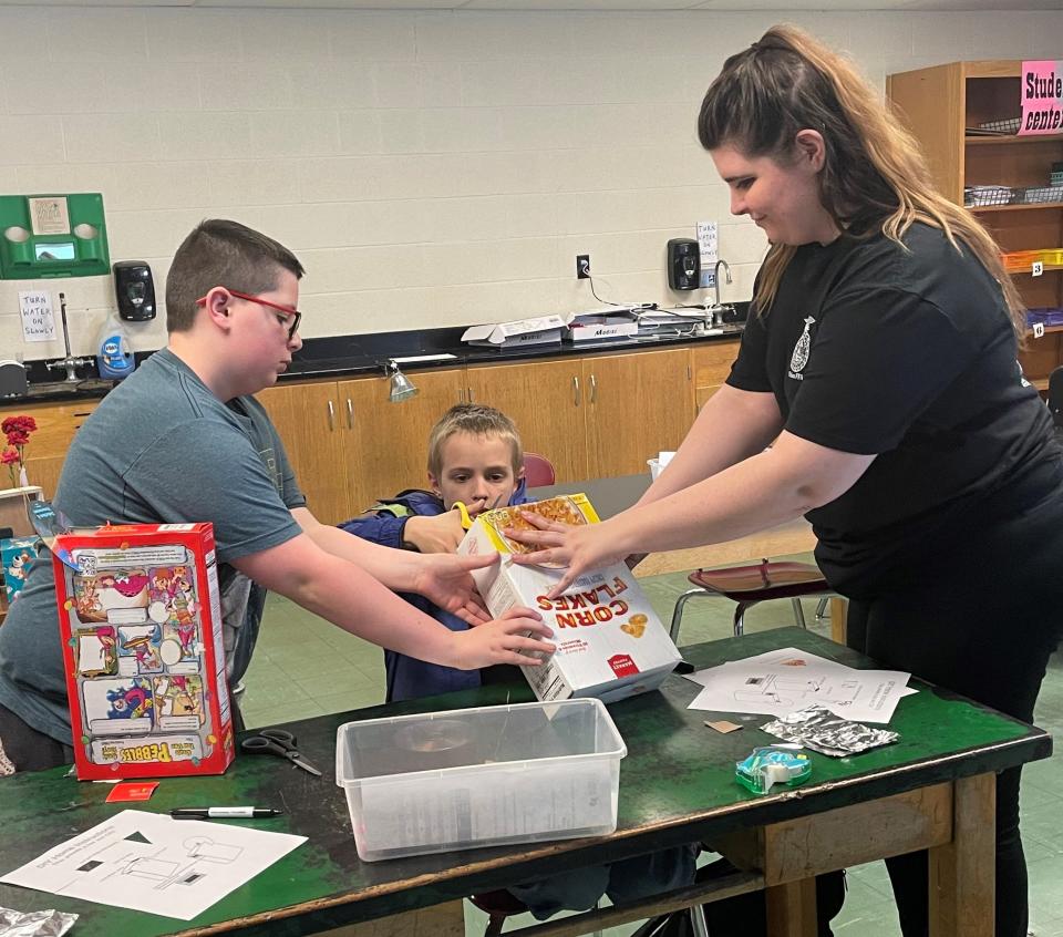 Utica Middle School math teacher Cassidy Rexrode and Jake Wells help Elias Atwood complete his CD spectrometer last week during a STEM project.