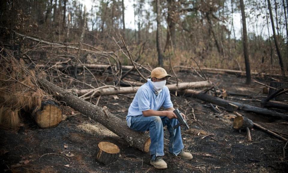 A masked man, member of Cherán’s security commission or ronda, stands guard in the forest.