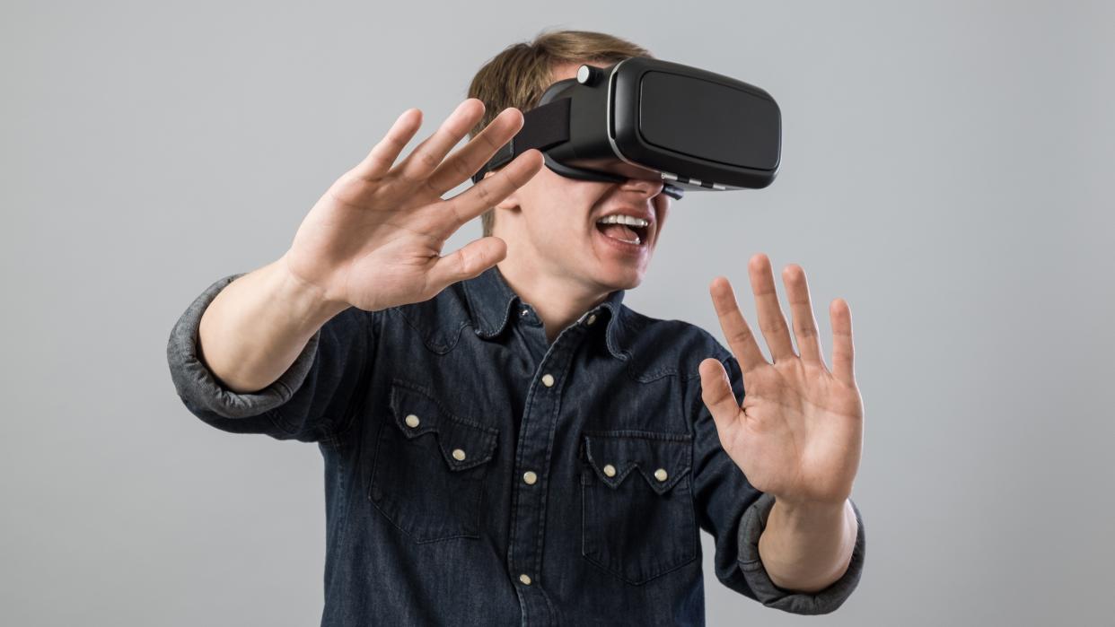  Man with hands out using a VR headset. 