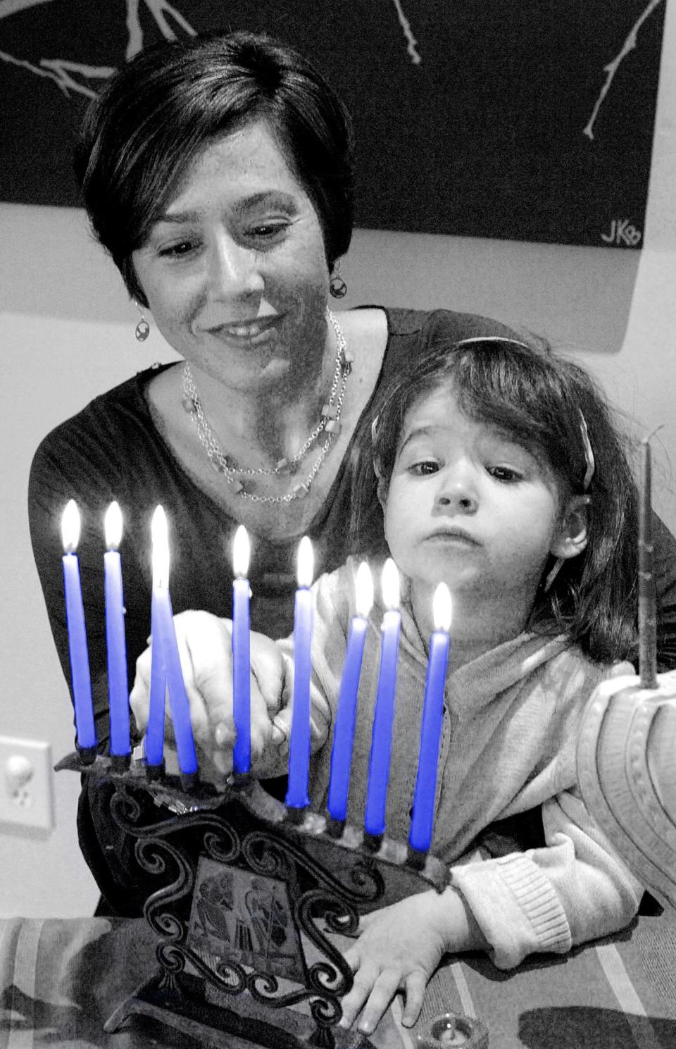 Jennifer Rivlin Roberts helps her daughter Isabel, 2, place the center candle into their family menorah, Friday, Nov. 9, 2007 in Atlanta.