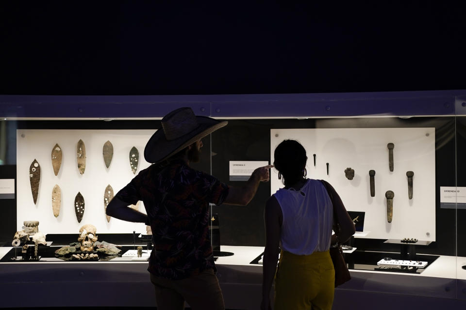 Visitors look at archaeological objects on display at the “Coyolxauhqui: The star, the goddess, the discovery” exhibit at the Museum of Templo Mayor, in Mexico City, Wednesday, March 29, 2023. The exhibit which marks the 45th anniversary of the discovery of a monolith depicting Coyolxauhqui, the Mexica lunar goddess, displays more than 150 objects focused on the mythology, symbolism and scientific research around this deity. (AP Photo/Eduardo Verdugo)