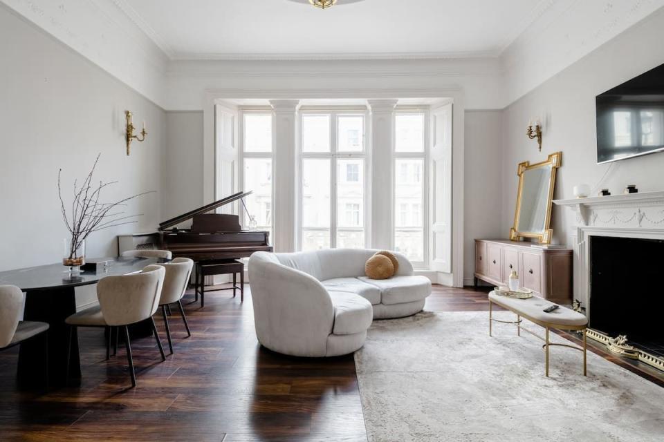 a living room with a piano and chairs