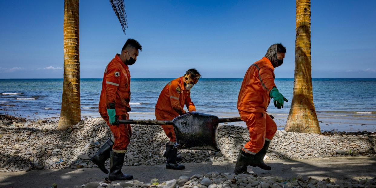 Coast guard members clean up an oil slick on March 8 in Pola, Oriental Mindoro.