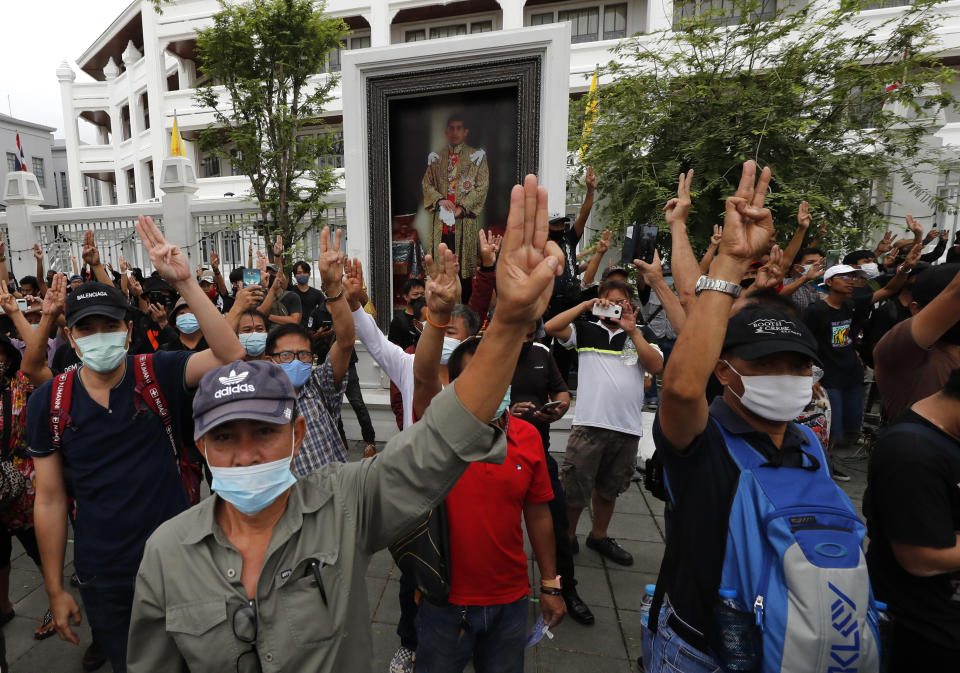 Pro-democracy protesters flash a three fingers, the movement's symbol of resistance salute, as they march close to Sanam Luang field in Bangkok, Thailand, Sunday, Sept. 20, 2020. Thousands of demonstrators who occupied a historic field in Thailand's capital overnight continued with their rally on Sunday to support the demands of a student-led protest movement for new elections and reform of the monarchy. A portrait of King Maha Vajiralongkorn is visible in the background. (AP Photo)