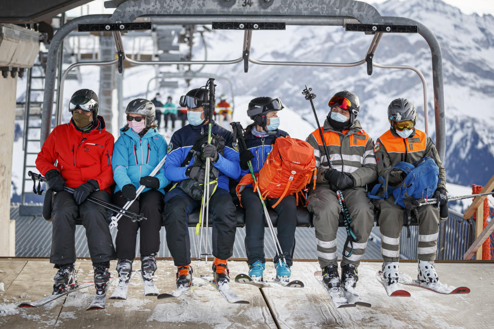 FILE - A policewoman and policeman, center, ride a ski lift as they patrol on the slopes and in alpine restaurants specifically, to check the application of sanitary measures during the coronavirus disease COVID-19 outbreak, in the alpine resort of Villars-sur-Ollon, Switzerland, Dec. 19, 2020. Switzerland is facing an exponential rise in coronavirus cases. But its federal government, hasn't responded with new lockdown measures. Experts say that's because the government's anti-COVID policies face a crucial test at the ballot box. On Sunday Nov. 28, 2021, Swiss voters will cast ballots on a 'COVID-19 law' that has unlocked billions of Swiss francs in aid for workers and businesses hit by the pandemic. (Valentin Flauraud/Keystone via AP, File)