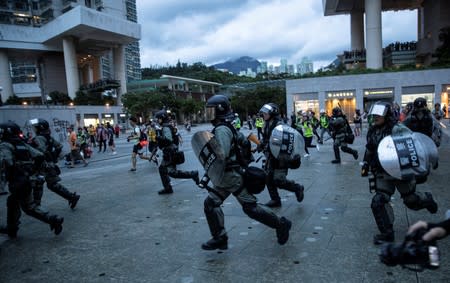 Police officers run looking for protesters at a metro station, in Hong Kong