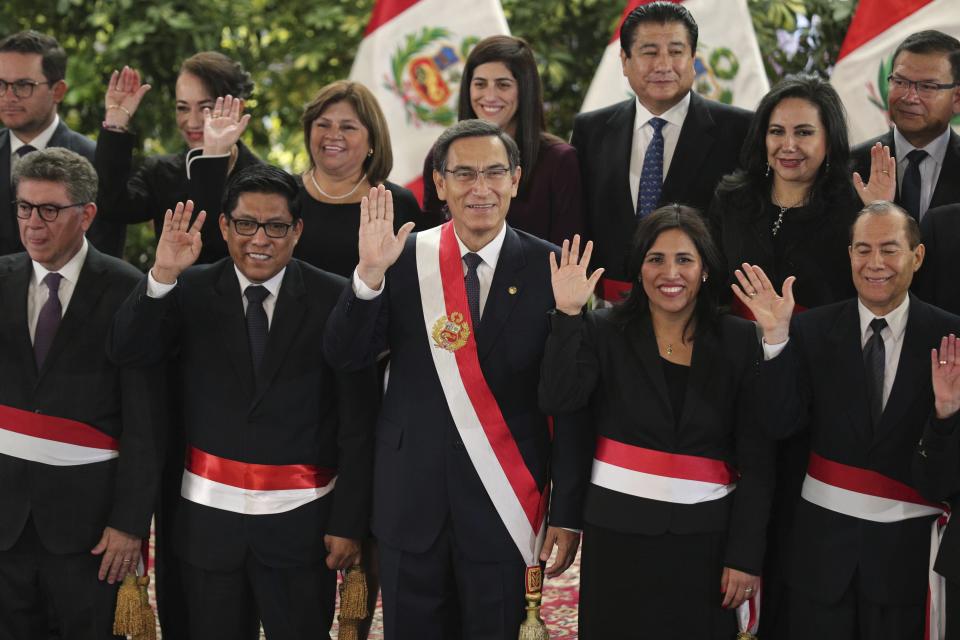 Peru's President Martin Vizcarra, center, waves as he stands with some members of his new cabinet, after their swearing-in ceremony at the government palace in Lima, Peru, Thursday, Oct. 3, 2019. The president and the new ministers will rule Peru without the congress that was dissolved on Monday. (AP Photo/Martin Mejia)