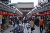 People wearing protective masks to help curb the spread of the coronavirus walk through a shopping arcade at the Asakusa district Tuesday, Nov. 24, 2020, in Tokyo. The Japanese capital confirmed more than 180 new coronavirus cases on Tuesday. (AP Photo/Eugene Hoshiko)