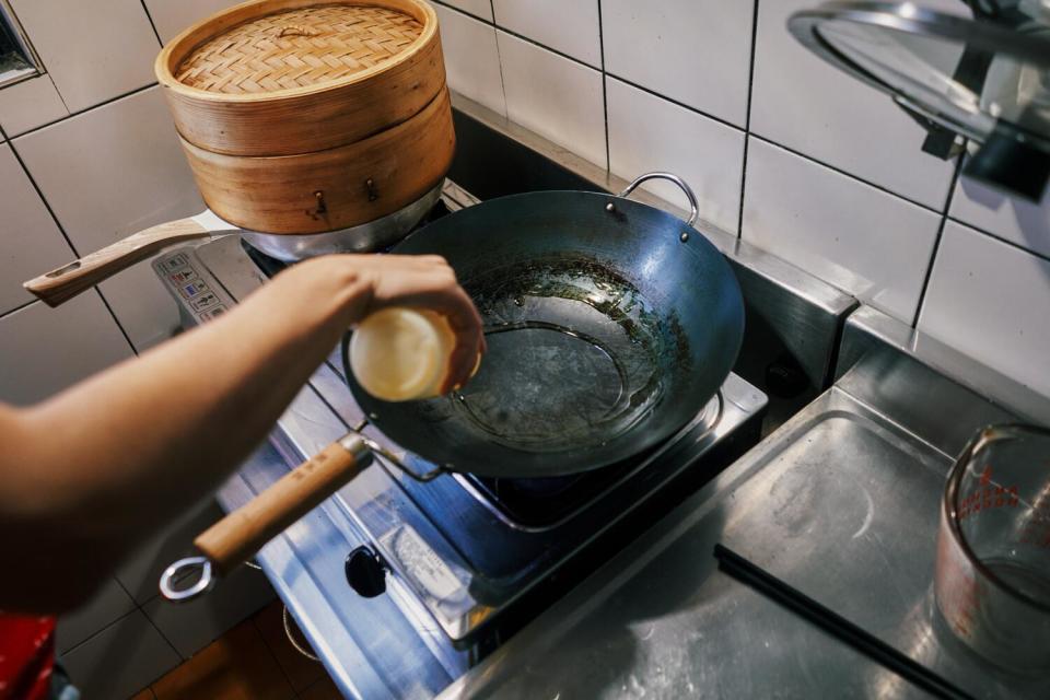 Heating oil in a wok in a tiled kitchen.