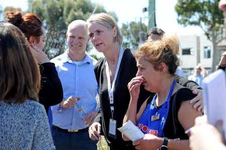 Employees of a local business comfort each other at the scene where a light plane crashed into their building near Essendon airport in Melbourne, Australia, February 21, 2017. AAP/Joe Castro/via REUTERS