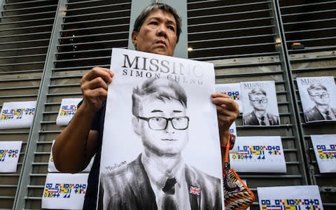 An activist holds an illustration of Simon Cheng during a gathering outside the British Consulate-General building in Hong Kong  - Credit: AFP