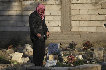 A man mourns at the grave of his son, who was a rebel fighter and whom he said was killed during clashes in Deir al-Zor, eastern Syria February 16, 2014. REUTERS/Khalil Ashawi