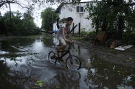 A youth cycles through a street flooded by Hurricane Rick in Lazaro Cardenas, Mexico, Monday, Oct. 25, 2021. Hurricane Rick roared ashore along Mexico's southern Pacific coast early Monday with winds and heavy rain amid warnings of potential flash floods in the coastal mountains. (AP Photo/Armando Solis)