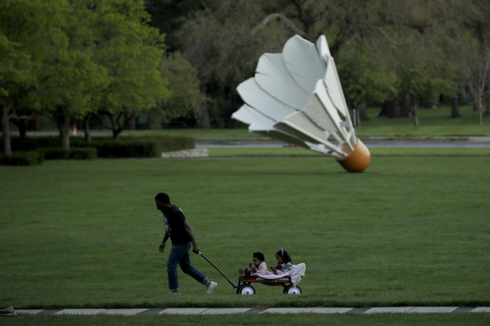 FILE - In this April 25, 2020, file photo, a man walks with his children at the Nelson-Atkins Museum of Art, in Kansas City, Mo. The museum remains closed as extended stay-at-home orders continue until May 15 in the city as part of an effort to stem the spread of the new coronavirus. (AP Photo/Charlie Riedel, File)