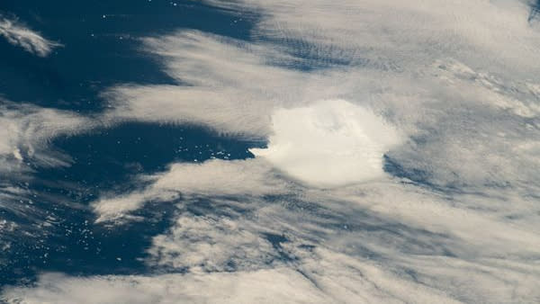  A white clump of iceberg sits below wispy clouds. 