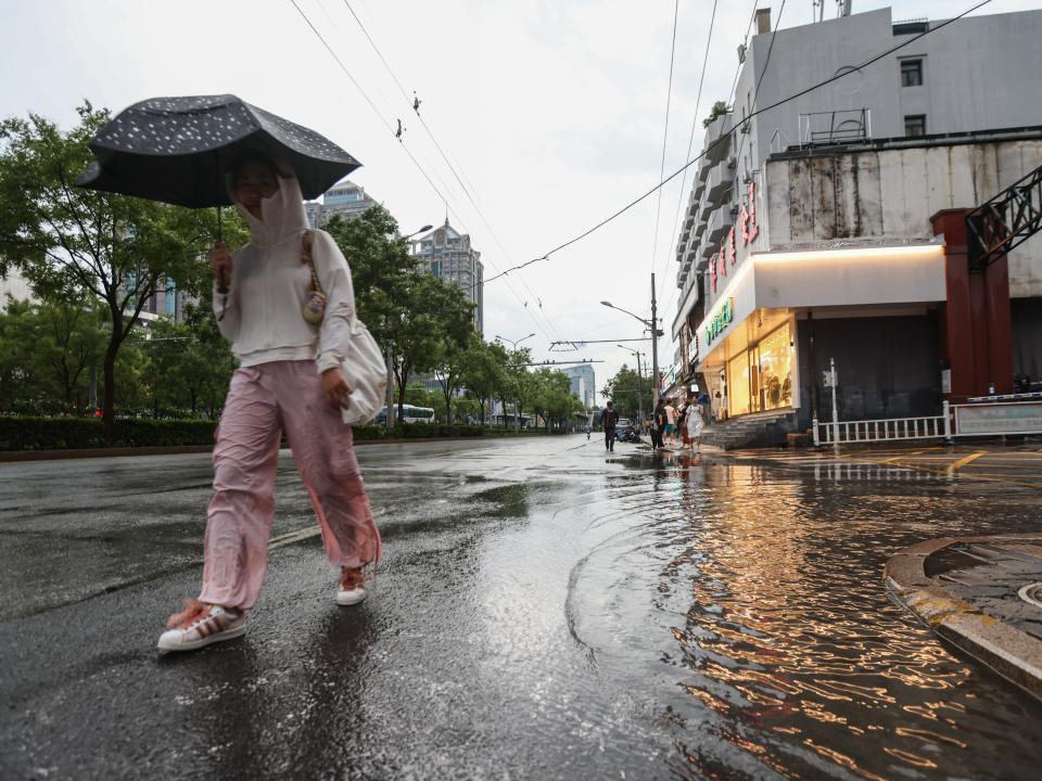 A woman walks with an umbrella during heavy rain, on a street in Beijing, China (EPA)