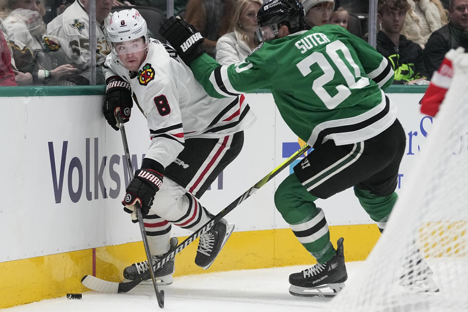 Chicago Blackhawks center Ryan Donato (8) and Dallas Stars defenseman Ryan Suter (20) try to control the puck during the second period of an NHL hockey game in Dallas, Friday, Dec. 29, 2023. (AP Photo/LM Otero)
