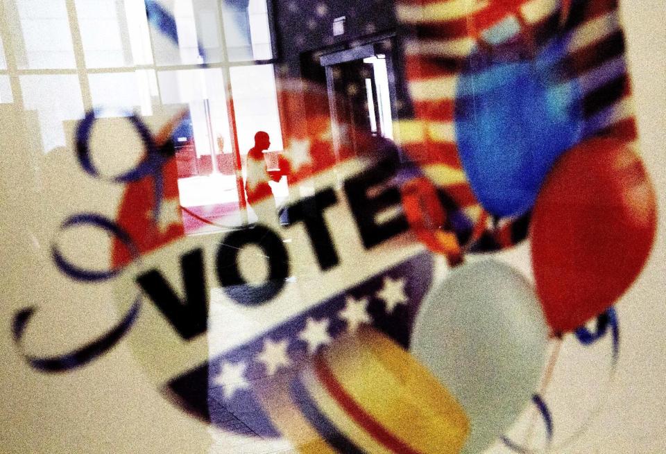 In this Nov. 1, 2016, photo, a voter is reflected in the glass frame of a poster while leaving a polling site in Atlanta, during early voting ahead of the Nov. 8 election day. Credit: AP Photo/David Goldman