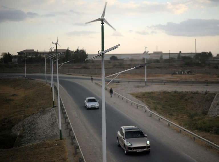 Street lamps powered by wind and solar energy line the side of a road in Kenya on August 19, 2015